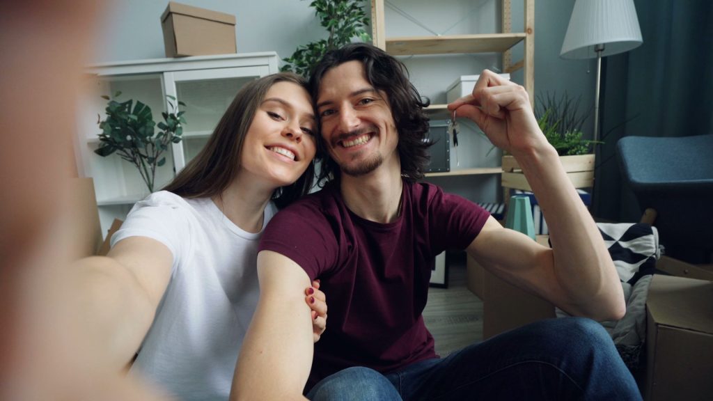 Jeune couple souriant qui tient les clés de son nouveau logement, s'établir en région